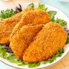 4 Air Fryer Fried Chicken Breasts on a plate, with fresh lettuce around the edges