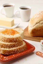 three slices of Anise Bread on a red square plate; full loaf to the right