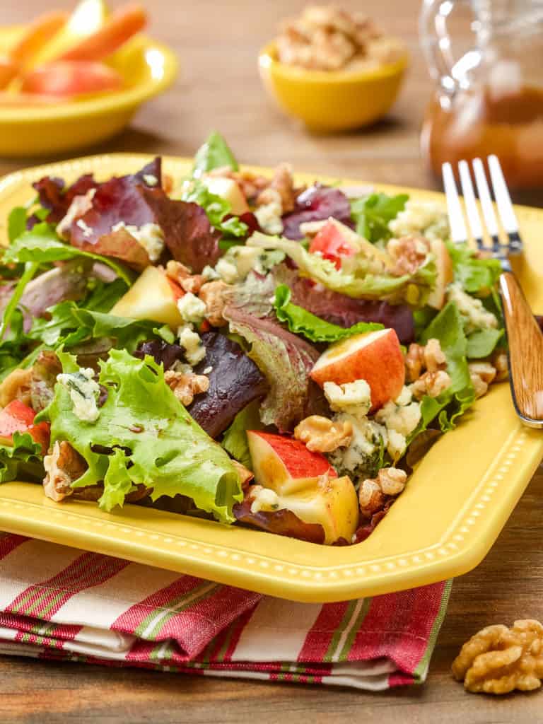 Square plate showing a generous serving of Mixed Green Salad with Apples, Walnuts and Stilton Cheese