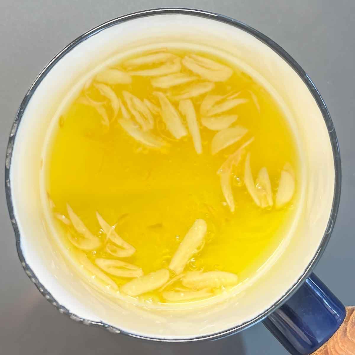 showing olive oil, garlic slices and salt simmering to make garlic-flavored oil