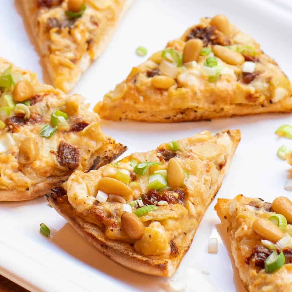 close up of artichoke, sun-dried tomato and feta triangles on a white plate