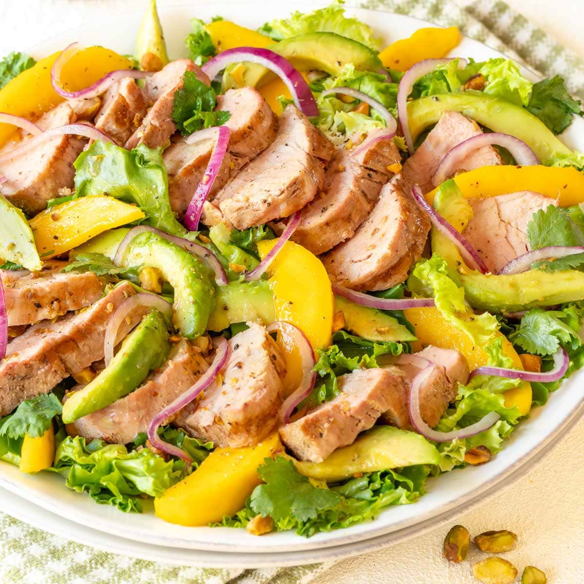 Close up of white platter holding Avocado Mango Salad with Pork Tenderloin