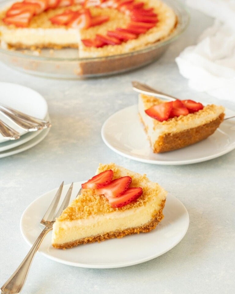 Two slices of Baked Cheesecake with the rest of the cake in the background
