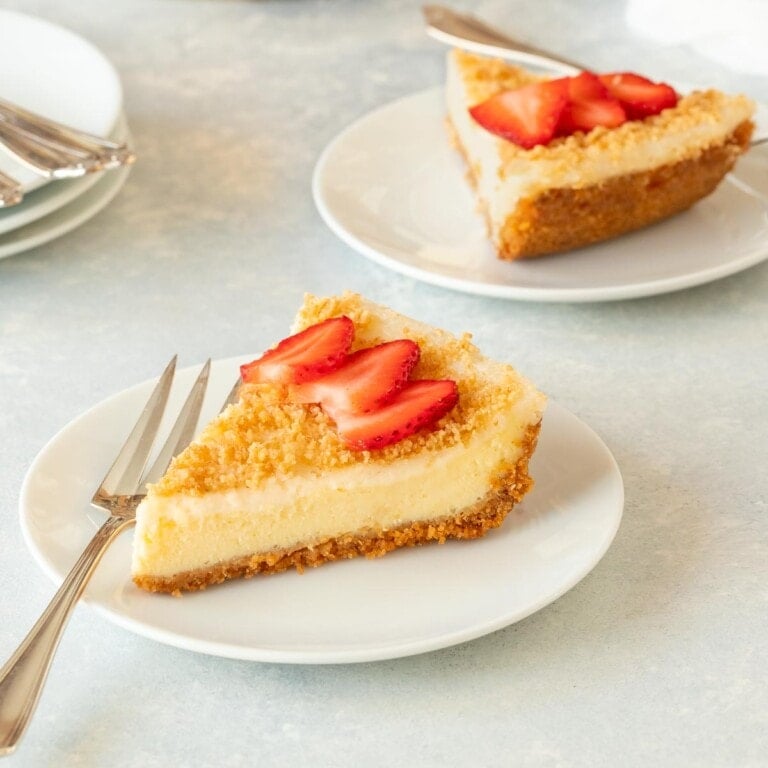 Two slices of Baked Cheesecake with sliced strawberries on top