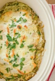 Overhead of white dish holding Baked Fish topped with a mayo sauce and sitting on shredded lettuce