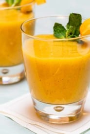 close up of 2 glasses holding banana mango smoothies