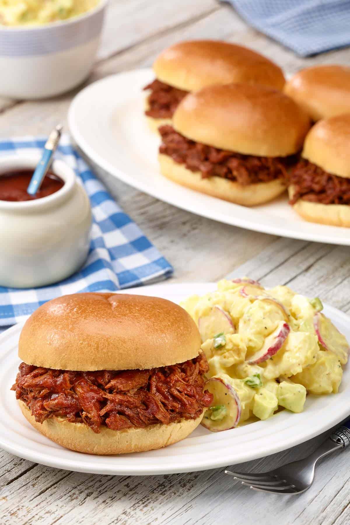 white plate holding a BBQ Beef Sandwich and Dorothy's Potato Salad