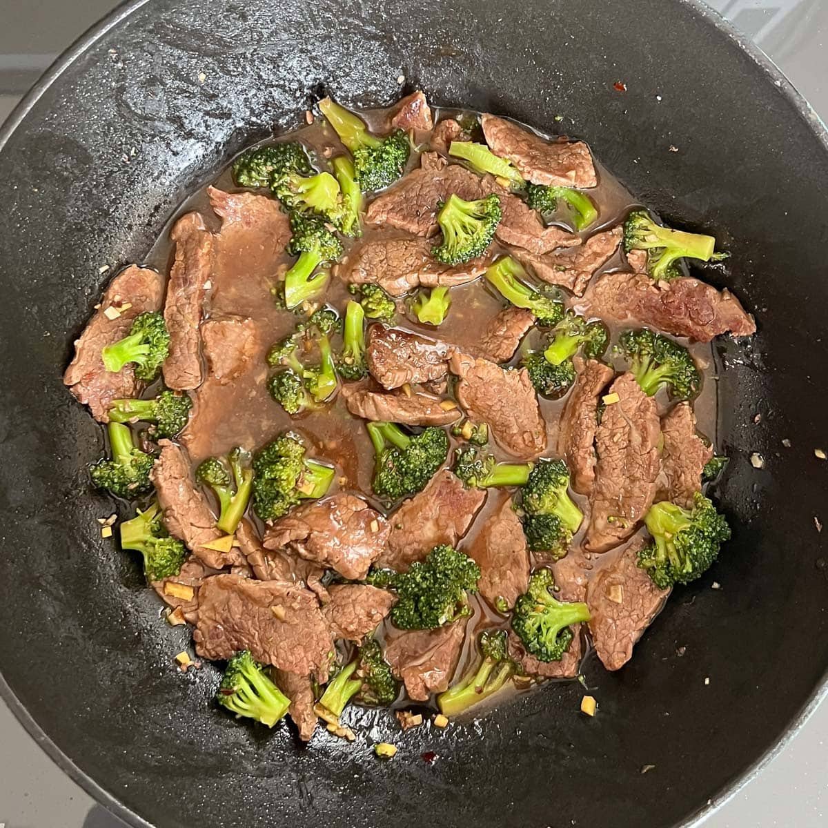 Cooked steak and broccoli in a heated pan to make beef and broccoli stir fry.
