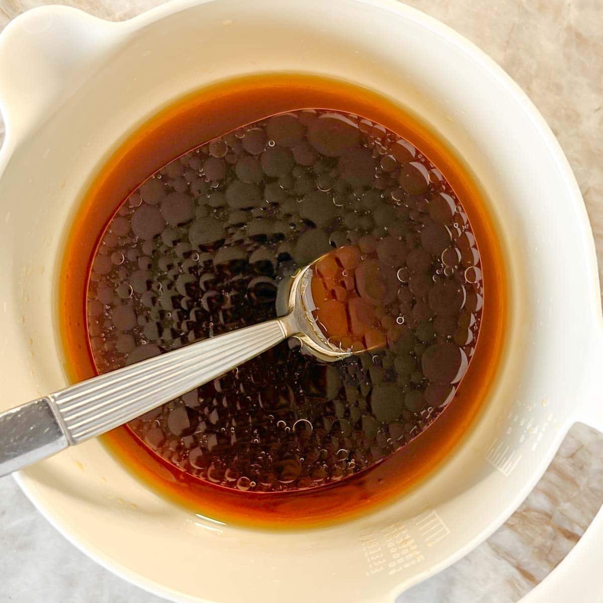 Beef and broccoli stir-fry sauce in a small mixing bowl with a metal spoon.