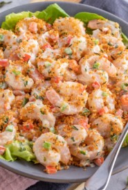 blue plate showing Shrimp Salad with Lime Herb Dressing; a serving spoon on the side