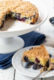 Blueberry Cake on a cake stand with a slice of cake
