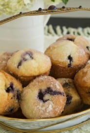 white basket filled with Lemon Blueberry Muffins, with flowers in the background