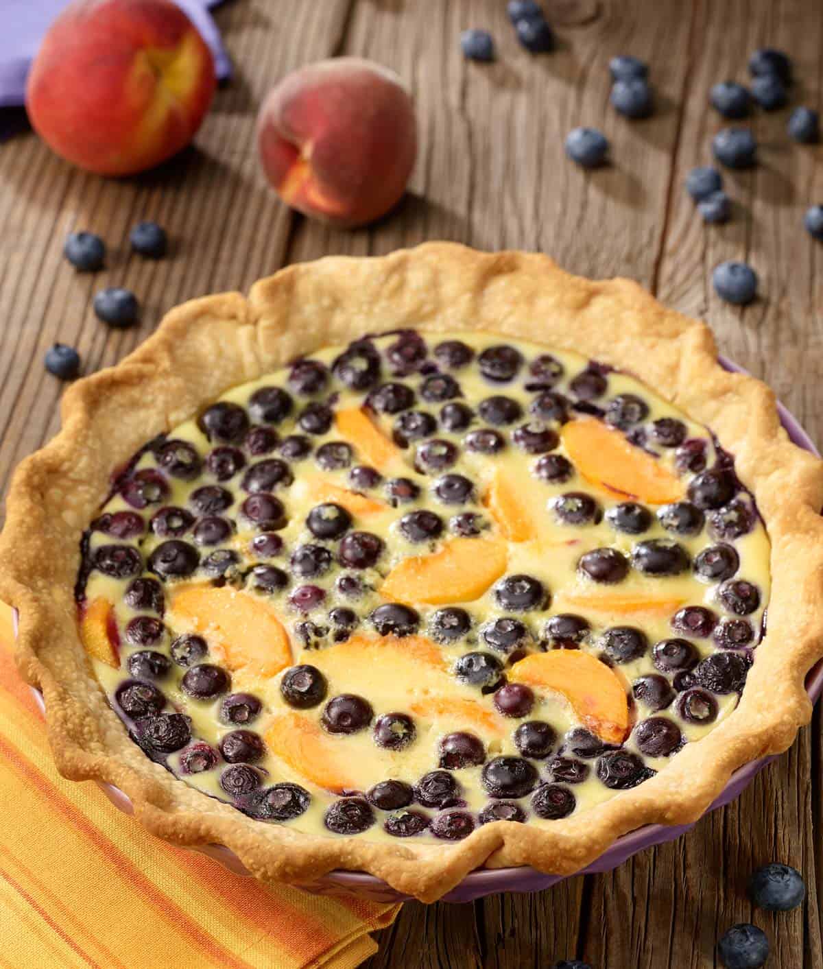 Blueberry peach custard pie with peaches and blueberries on the side