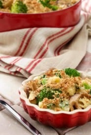 small red dish with broccoli,mushroom, spinach and cheese pasta with larger pot in the background