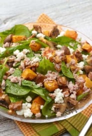 Roasted buttrnut squash and mushroom spinach salad in a glass bowl