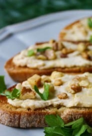 portions of 3 bruschetta topped with bean puree, on a blue plate