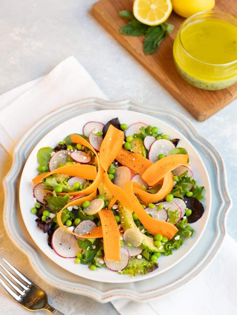 Shaved carrots, radishes and sweat peas arranged with lettuces and avocado and lemon basil vinaigrette