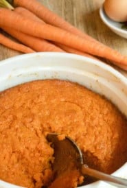 white dish of Roasted Carrot Souffle, with a spoon scooping out a portion