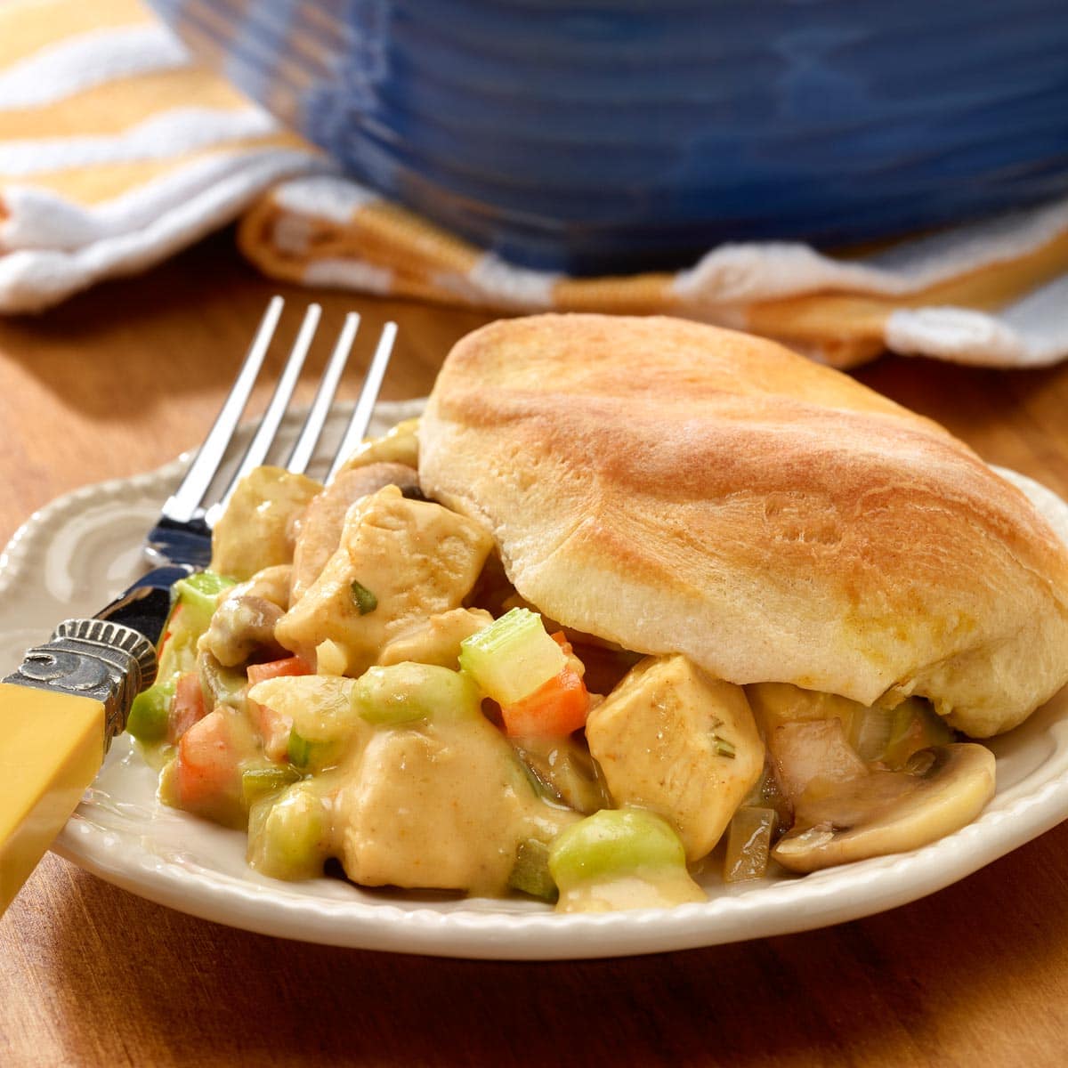 plate holding one portion of chicken pot pie with biscuits