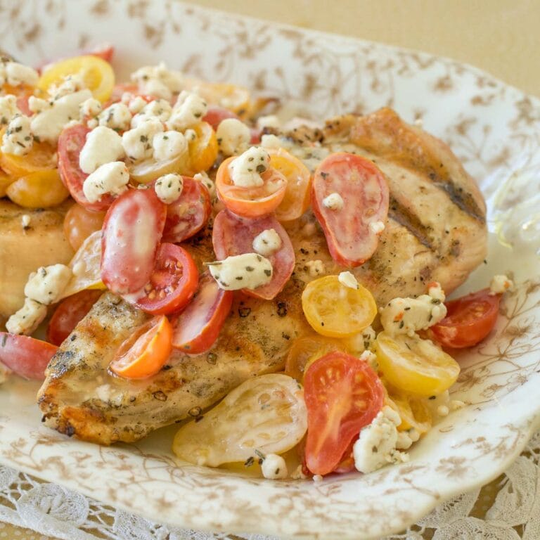 Gold and white platter holding Grilled Chicken with Tomatoes and Goat Cheese