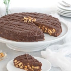Biscuit cake on a cake stand with a slice on a plate in front