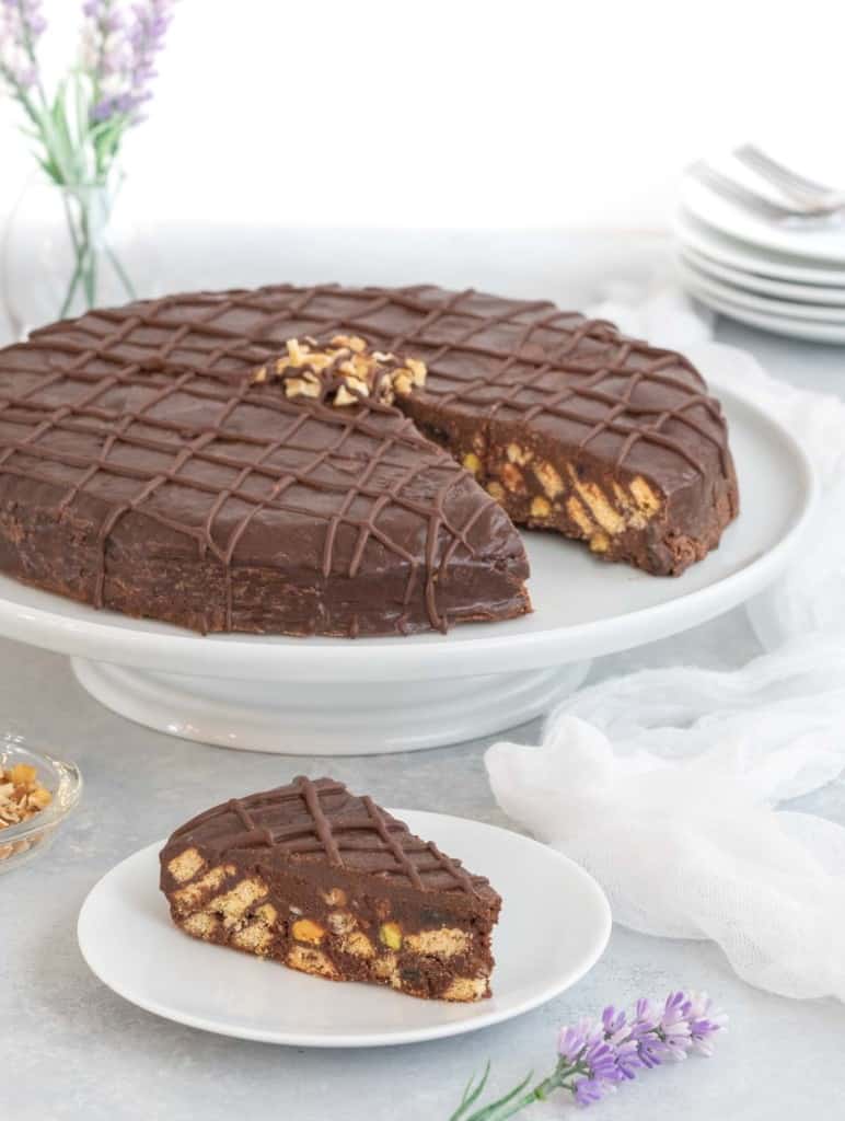 Biscuit cake on a cake stand with a slice on a plate in front