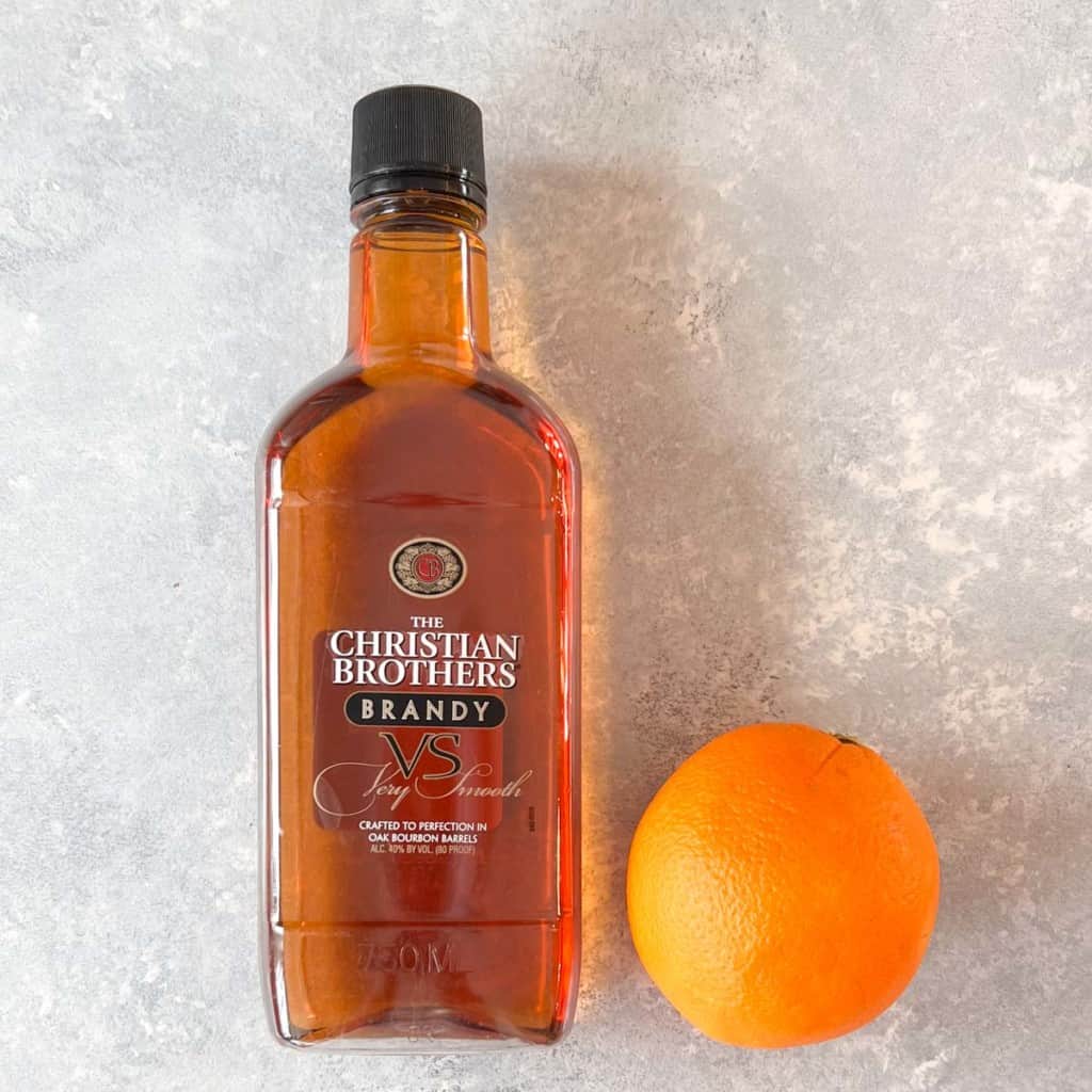 brandy bottle next to a navel orange, showing optional ingredients for biscuit cake