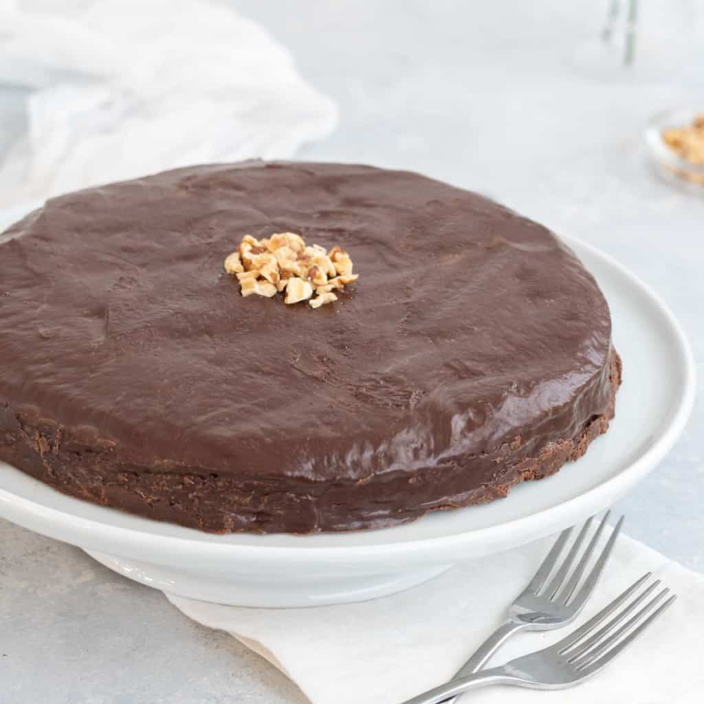 Chocolate Biscuit Cake on a white cake platter, with walnut garnish