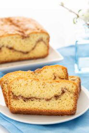 3 slices of Homemade Cinnamon Swirl Bread on a white plate, with the loaf behind