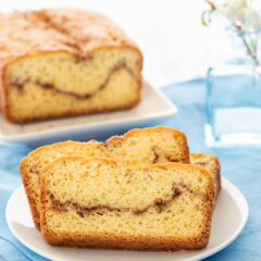 3 slices of Homemade Cinnamon Swirl Bread on a white plate, with the loaf behind