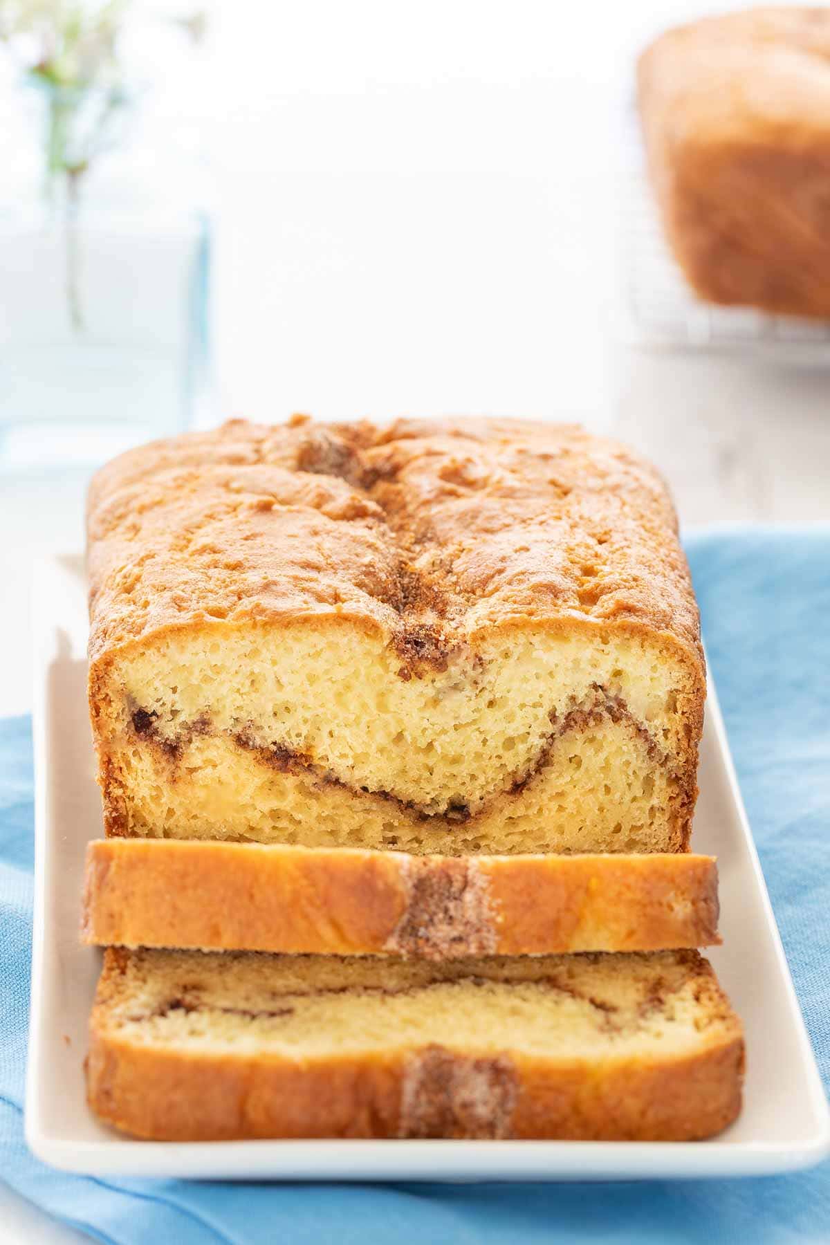 Loaf of Cinnamon Swirl Bread with two slices cut in front and lying down