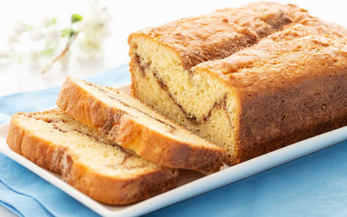 Side view of a loaf of Homemade Cinnamon Swirl Bread with two slices at an angle, showing the inside