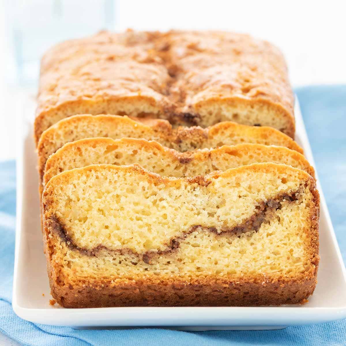 Loaf of Cinnamon Swirl Bread with 3 slices in front standing at an angle, showing the inside