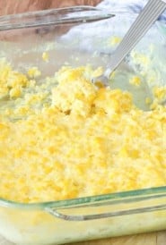 cooked corn pudding in a glass dish, with a portion removed