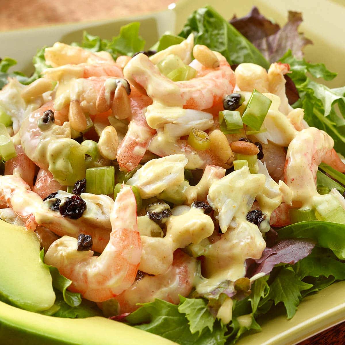 Serving platter with Crab and Shrimp Salad atop mixed greens with sliced avocado alongside