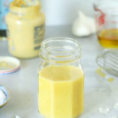 Mason jar filled with Dijon Mustard Vinaigrette, surrounded by its ingredients