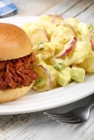 white plate with Dorothy's PotatoPotato Salad shown next to BBQ Beef sandwich