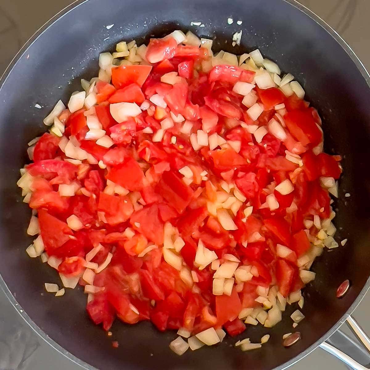 Tomato, onion and garlic cooking in a large saauté pan