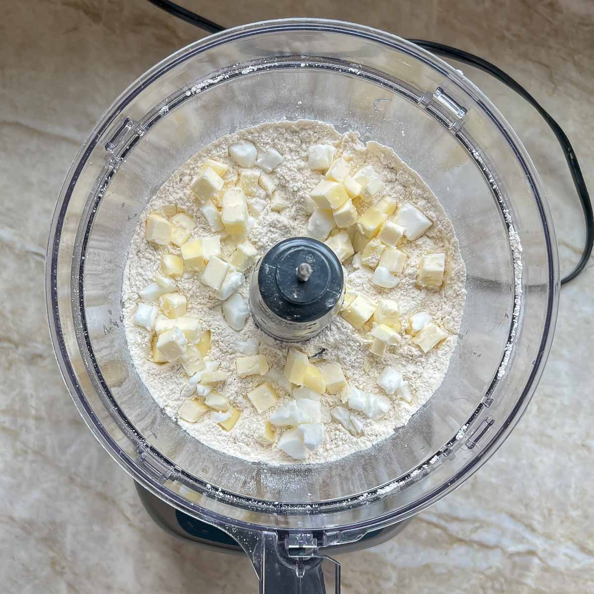 Fat cubes added to dry ingredients in bowl of food processor