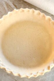 unbaked pie crust in a pie plate, with edge crimped and bottom poked with a fork