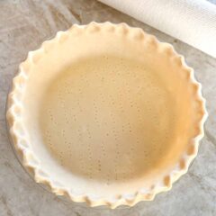 unbaked pie crust in a pie plate, with edge crimped and bottom poked with a fork
