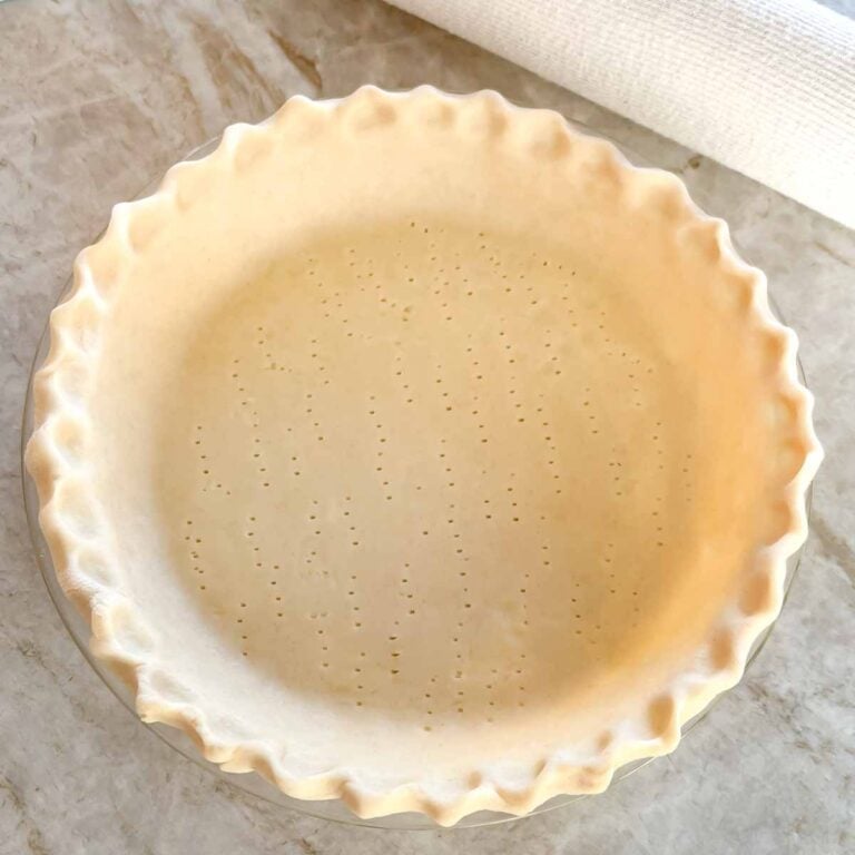 unbaked pie crust in a pie plate, with edge crimped and bottom poked with a fork
