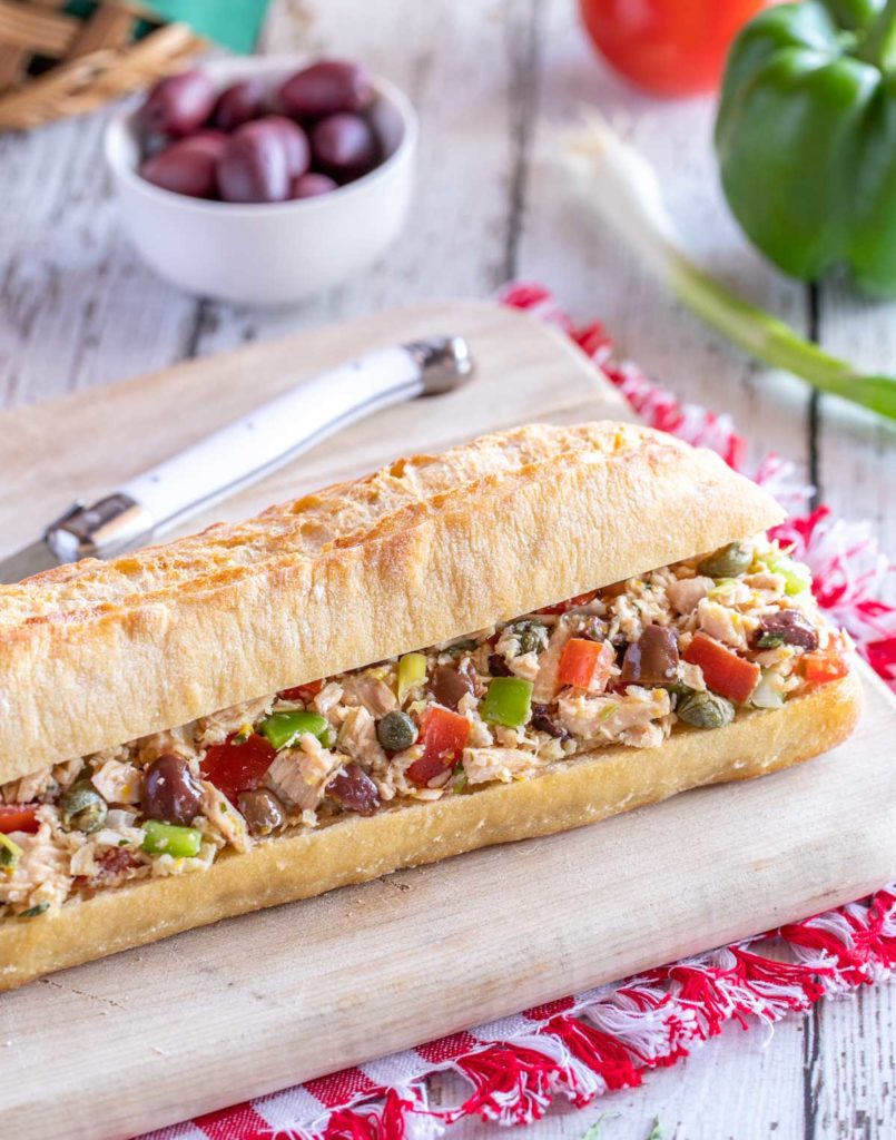 Cutting board holding Pan Bagnat - a french baguette stuffed with tuna nicoise filling.
