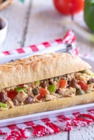 white platter holding a Pan Bagnat - crusty french baguette fiiled with Tuna Nicoise