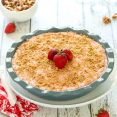 Deep dish blue pie plate holding a Frozen Strawberry PIe, garnished with 3 strawberries