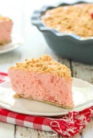 slice of Frozen Strawberry Pie on a white plate with rest of pie in the background