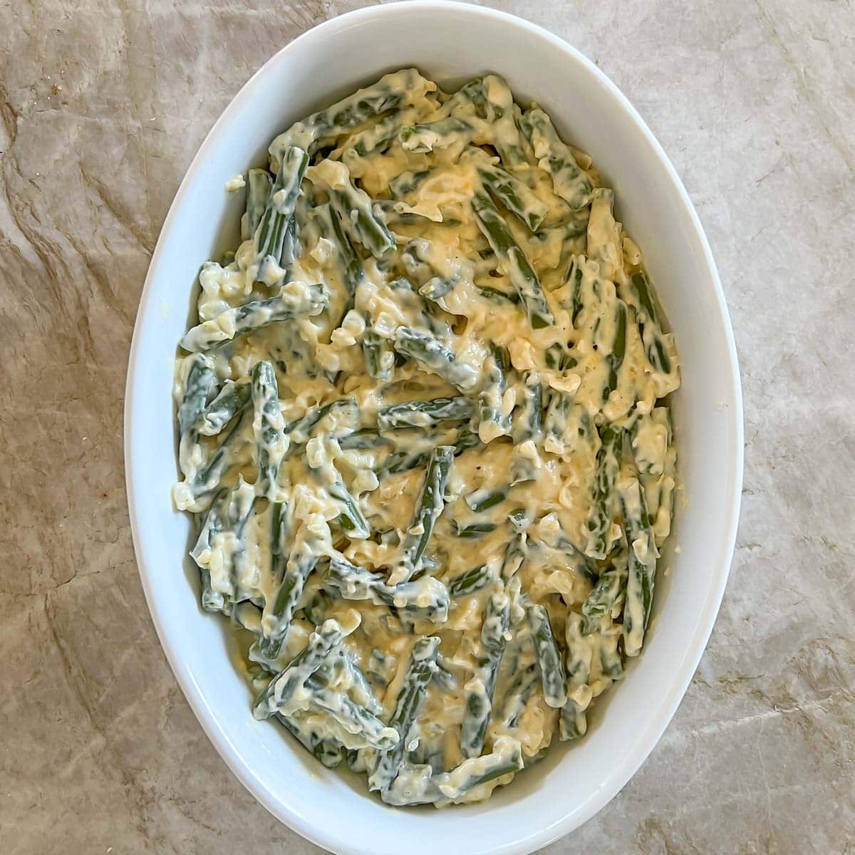 Process shot - green beans mixed with cheese sauce and in baking dish, ready to be baked
