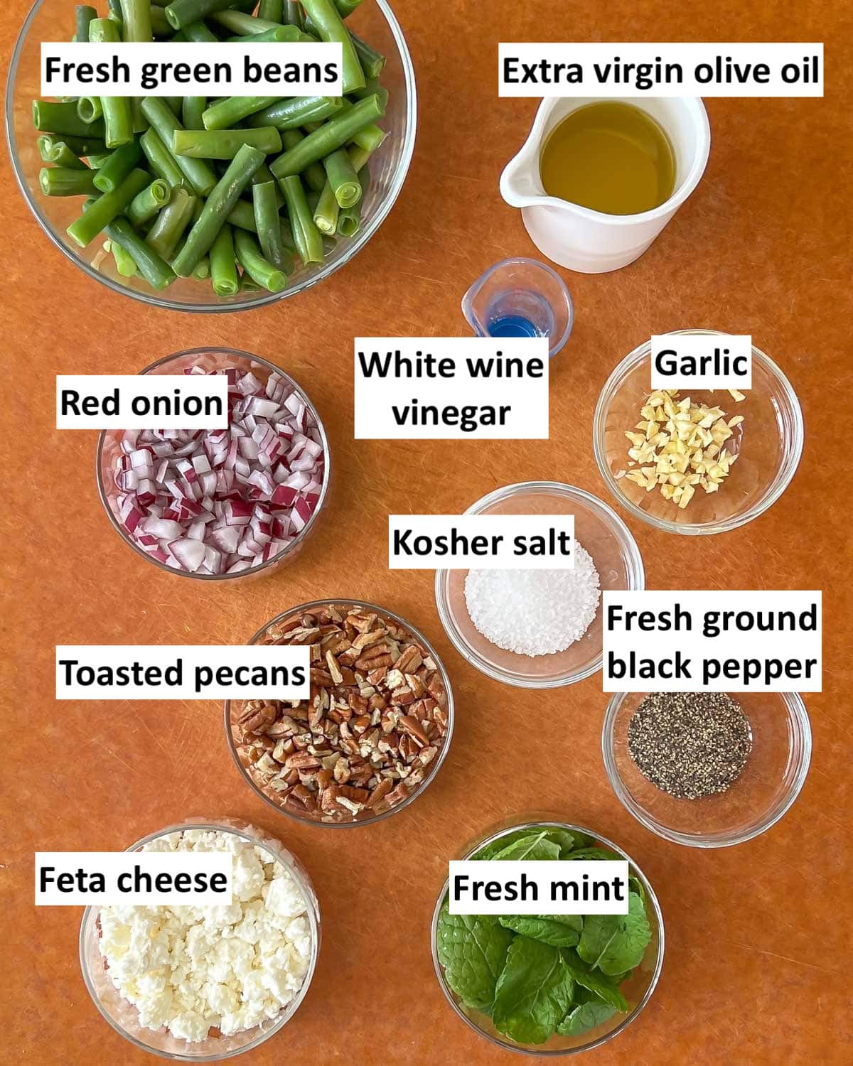 cutting board holding all ingredients in cold green bean salad, with labels