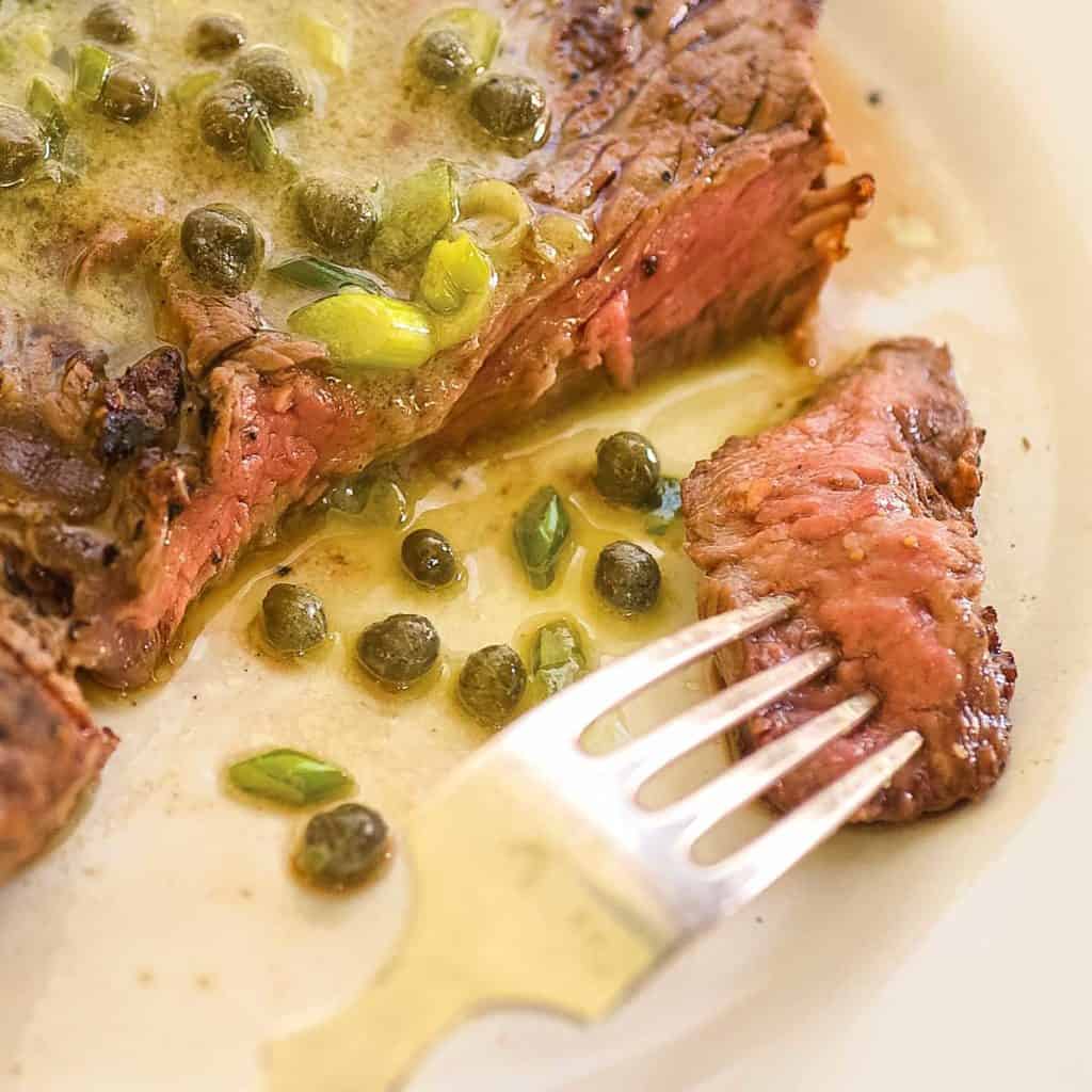 close up of a bite of grilled ribeye steak on a fork