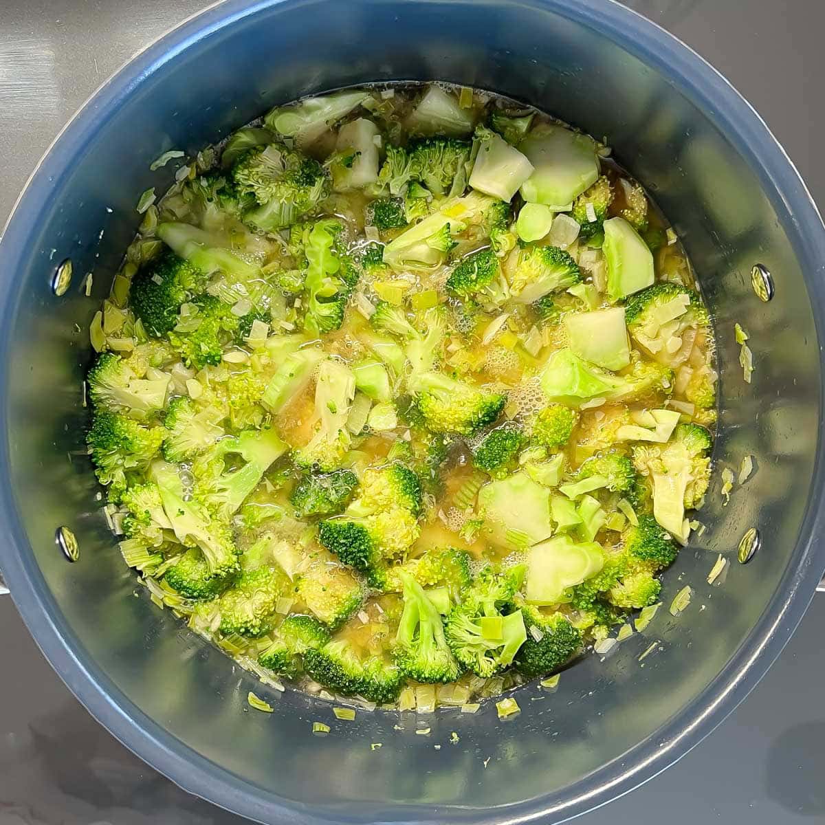 Broccoli soup ingredients in large pot on stovetop, simmering